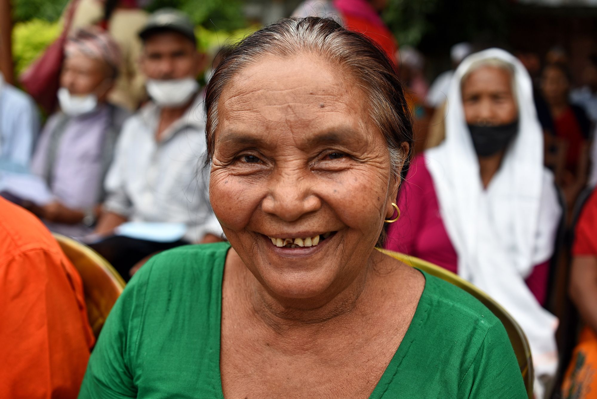 A patient wearing green smiling to the camera following her cataract surgery. 